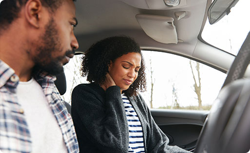 A man and woman sitting in a car's driver's seat, potential personal injury risk - Whitley-Sebti Law